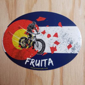 Fruita Female Mountain Bike Rider coming out of a grunge Colorado flag